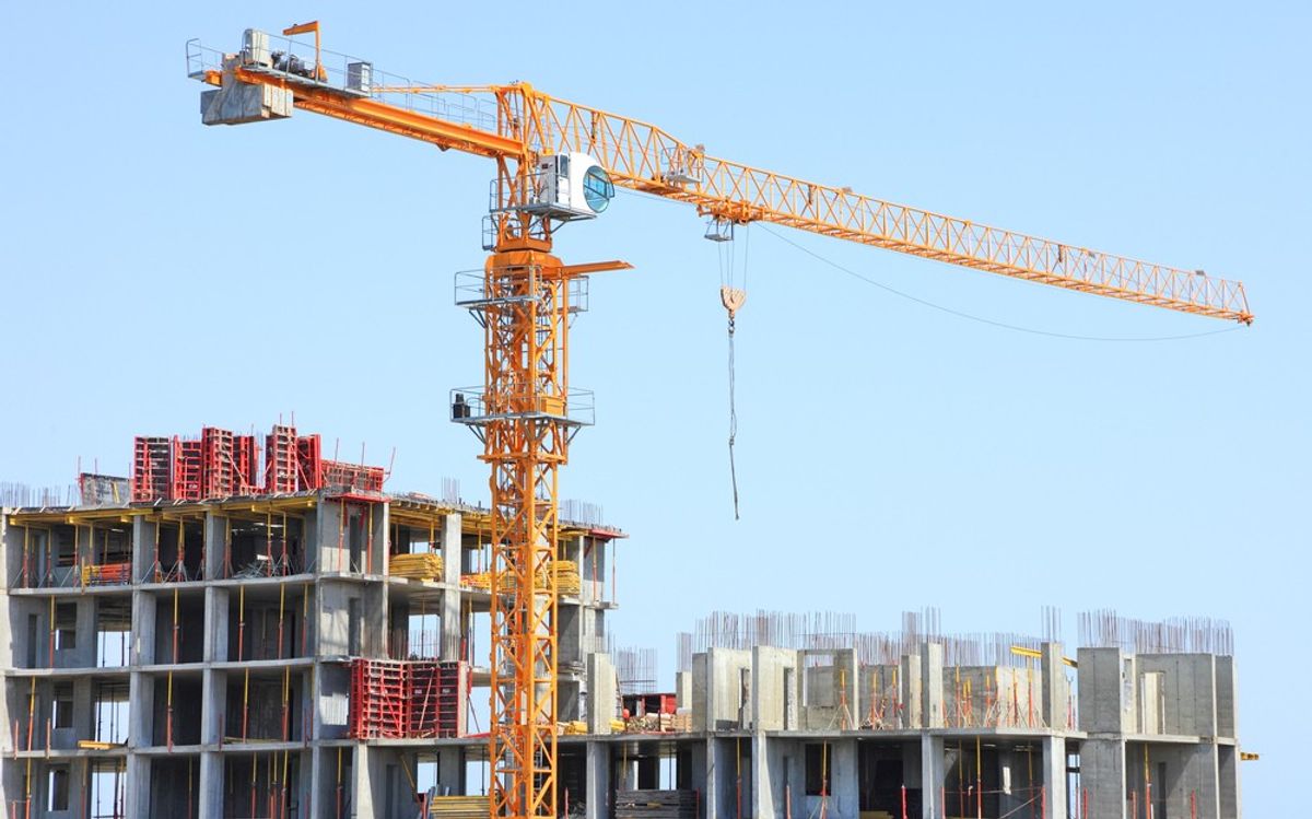 A crane sits above a building under construction