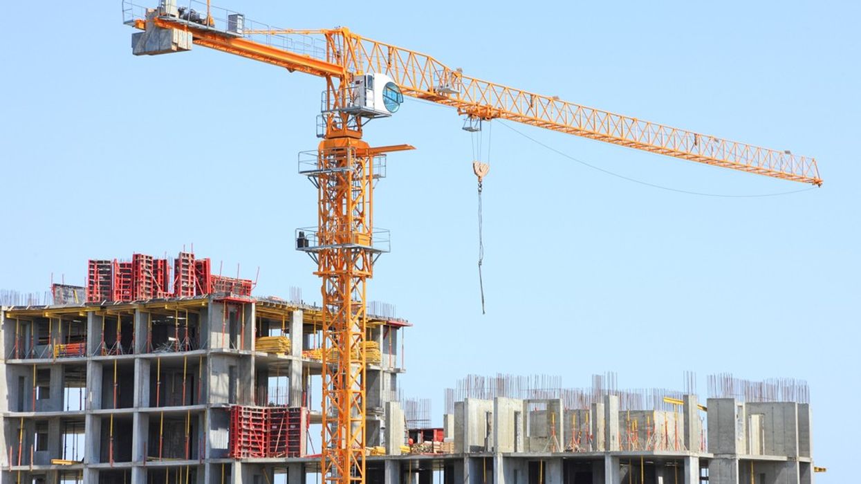 A crane sits above a building under construction