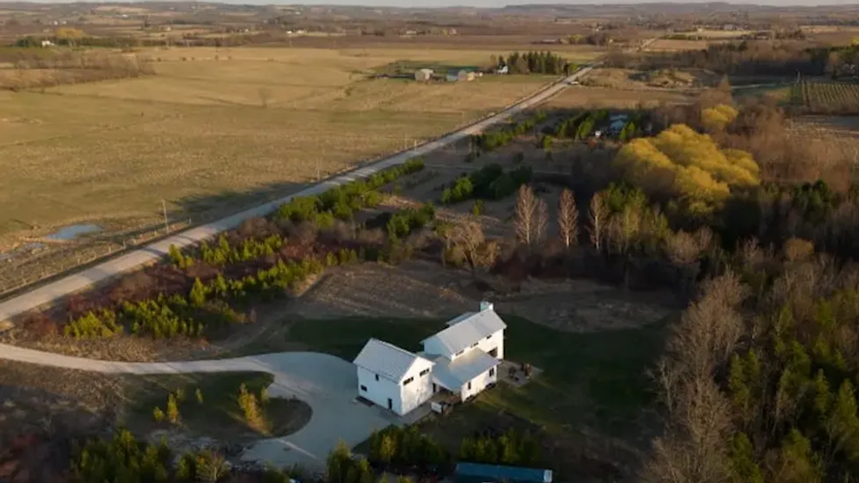Aerial view of saltbox-style home surrounded by rural land