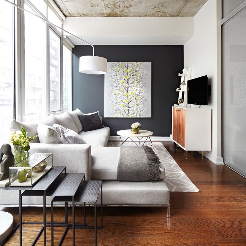 An art piece to give the black wall a bit of pop, some couch accessorizing, and a sleek side table with some greenery add a pop of colour to the neutral paint tone. (Photo by Lisa Petrole)