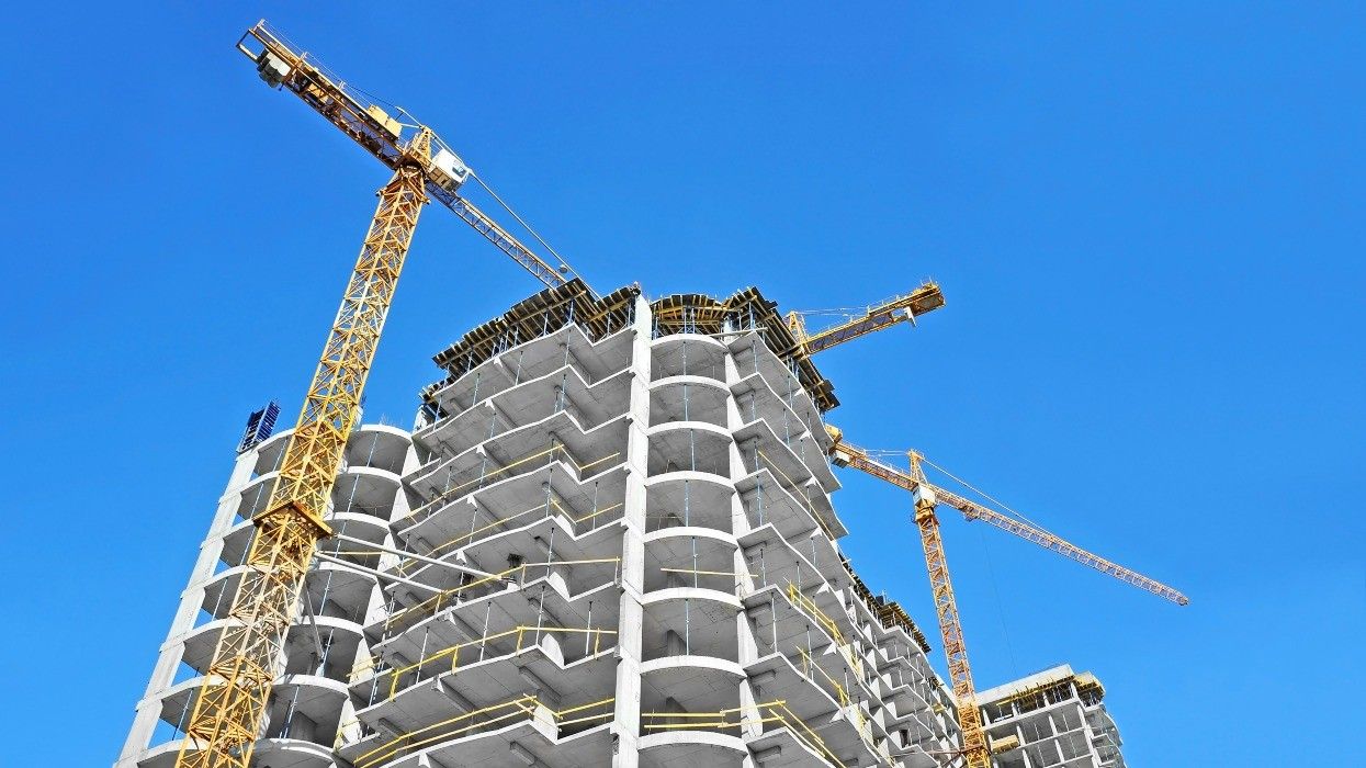 Cranes above a concrete building under construction.