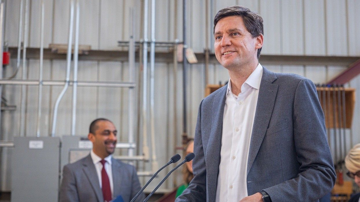 Premier David Eby at a lectern, with Minister of Housing Ravi Kahlon in the background.