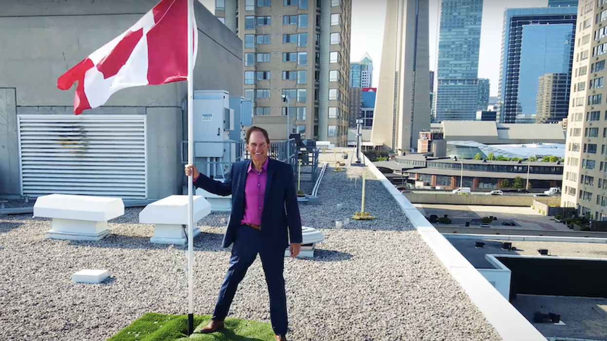 Real estate agent on a rooftop, holding a Canadian flag as it blows in the wind
