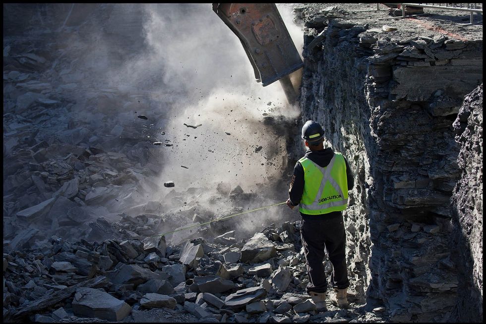 The excavator chisels its way through the shale bedrock of Torontos South Core, an area of the city south of King Street down to the lake, where the shale bedrock is close to the surface at the lakefront about 10 metres down. Chiseling out the ancient sedimentary rock is the only practical way to excavate the site when deep enough to reach the shale.