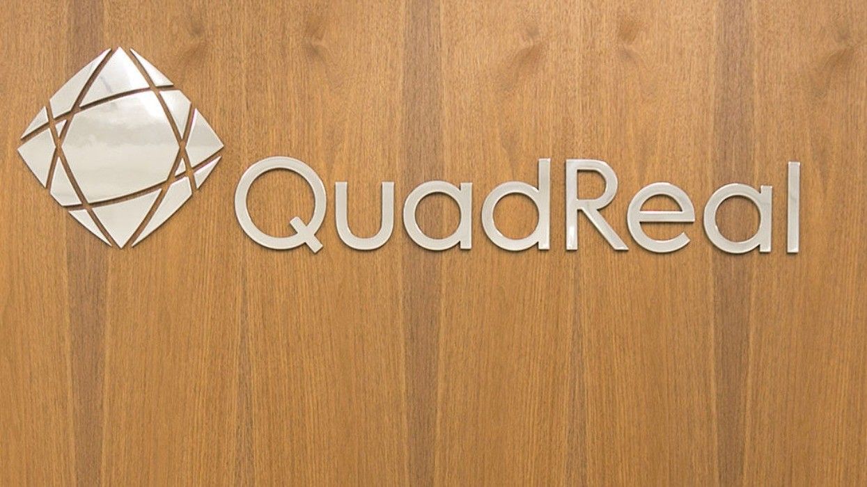 The QuadReal logo on a wooden wall.