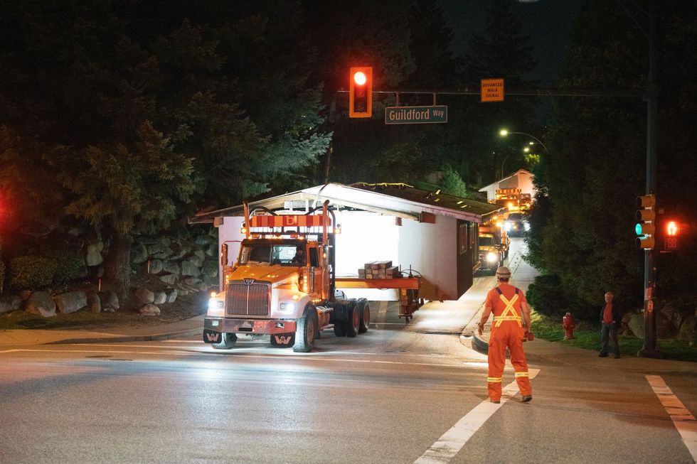 Trucks transporting homes through city streets.