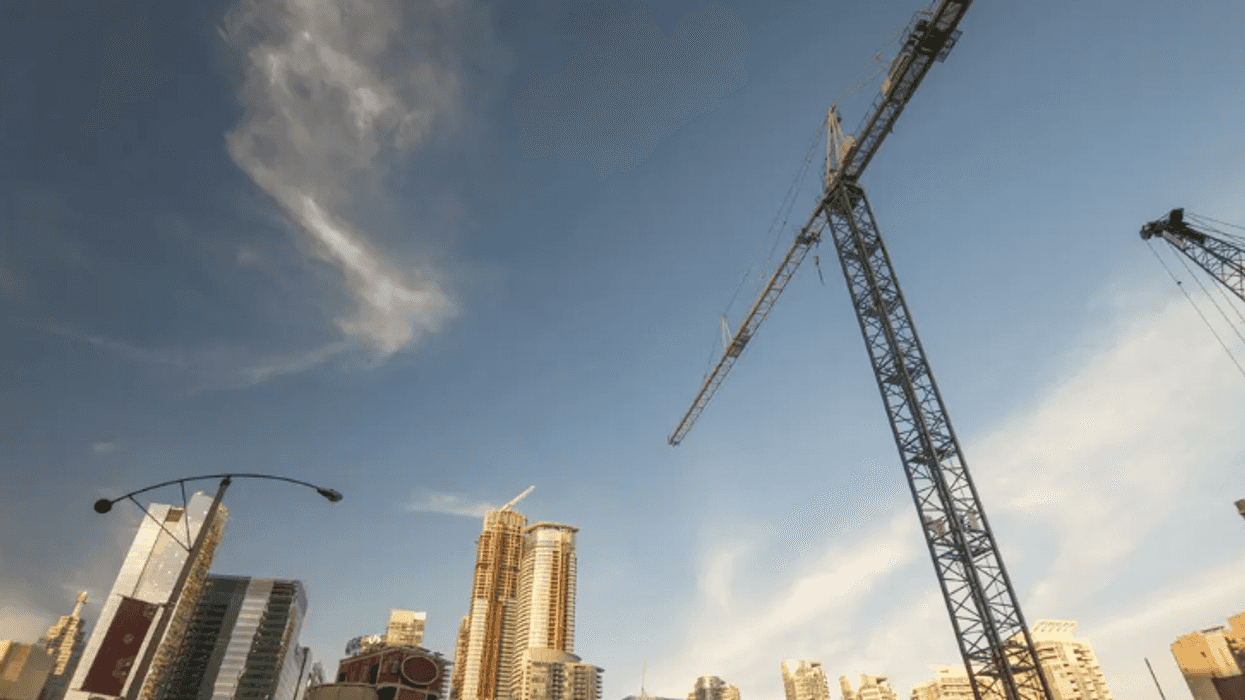 Urban centre with crane at the forefront and blue skies overhead