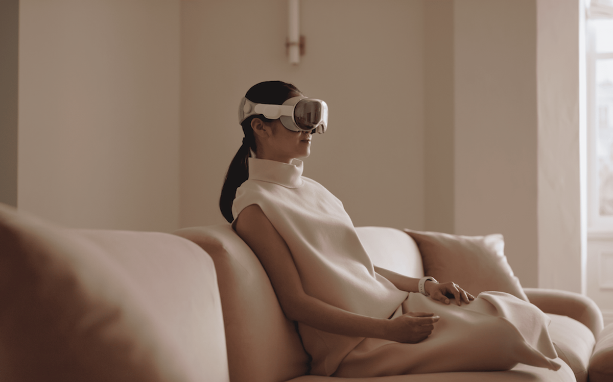 Woman seated on couch, wearing Apple Vision Pro headset