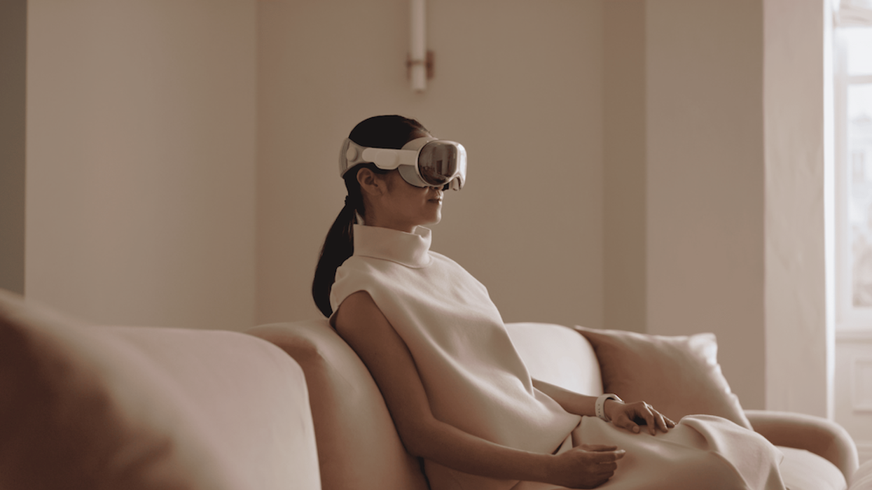 Woman seated on couch, wearing Apple Vision Pro headset